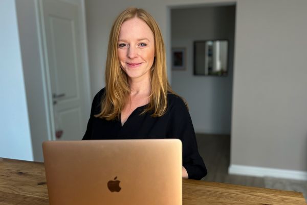 Svenja Adamek lächelt, vor ihr ein aufgeklapptes Macbook.