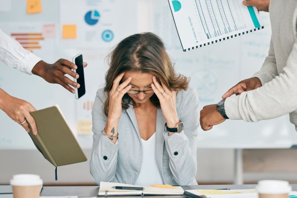 Frau stützt ihren Kopf in die Hände, um sie herum viel Arbeit