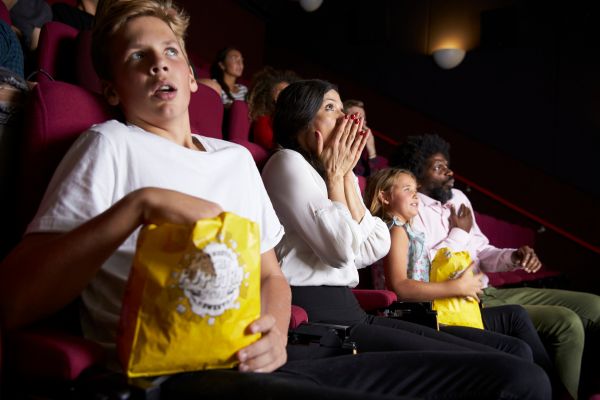 Menschen im Kino, schauen auf die Leinwand und sind erschrocken